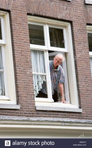 holland-amsterdam-man-looking-and-leaning-out-of-the-open-window-of-AR2XC1.jpg